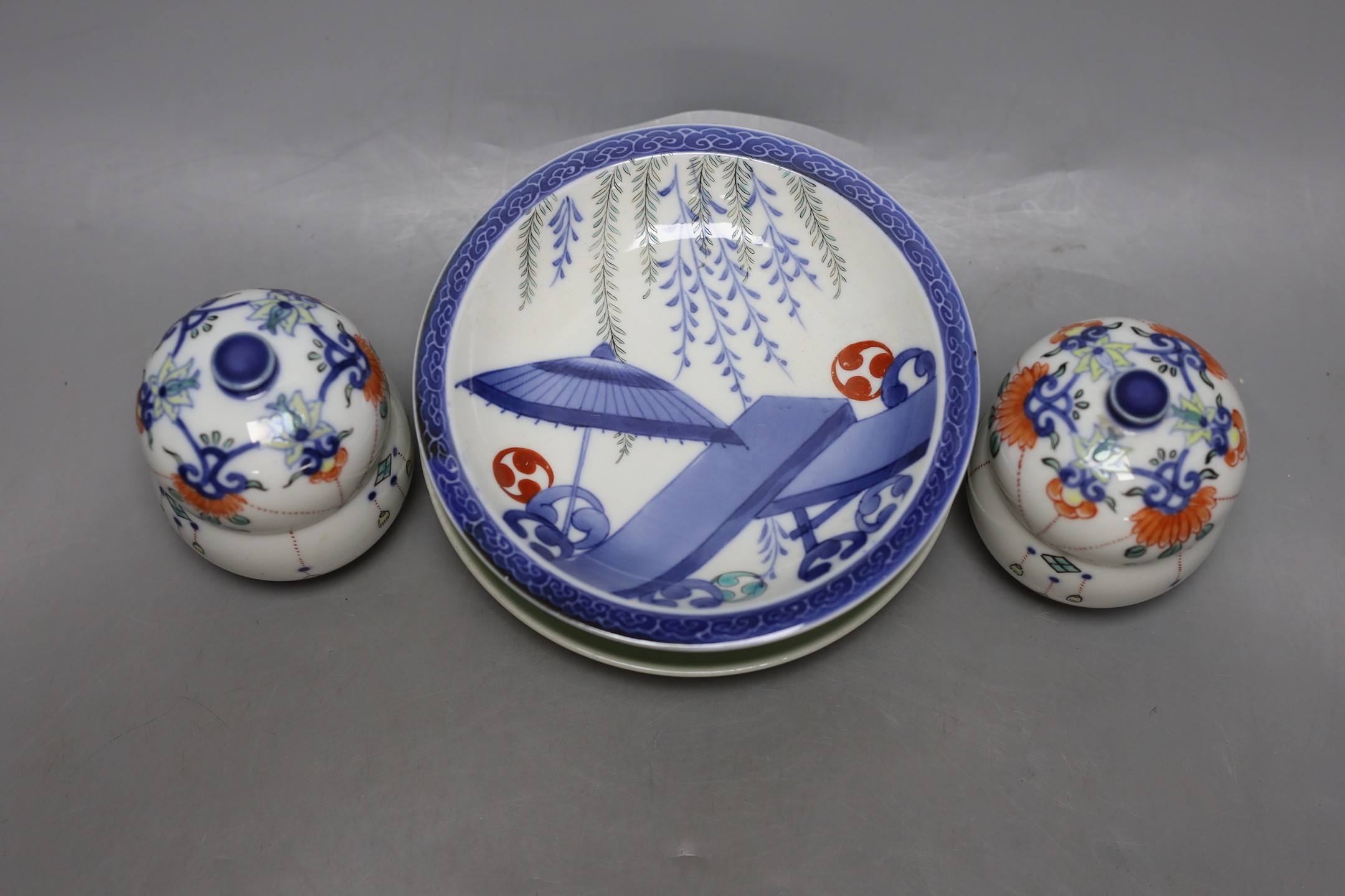 A pair of Japanese Nabesima style jars and covers and a similar footed dish, together with a Japanese Satsuma bowl, 11cm diameter and two plates (5)